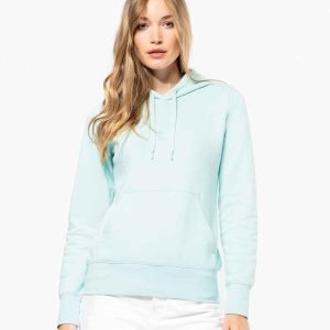 Woman wearing the KB4028 Kariban Ladies Eco-Friendly Hooded Sweatshirt in soft pastel, blending eco-conscious living with fashion.