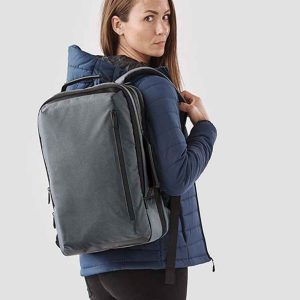 Professional woman with a KNX2 Stormtech Hedmark Commuter Backpack, an essential for the stylish commuter.
