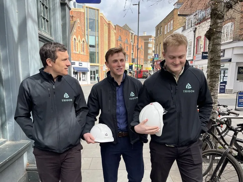 A small team in branded softshell jackets carrying branded hard hats