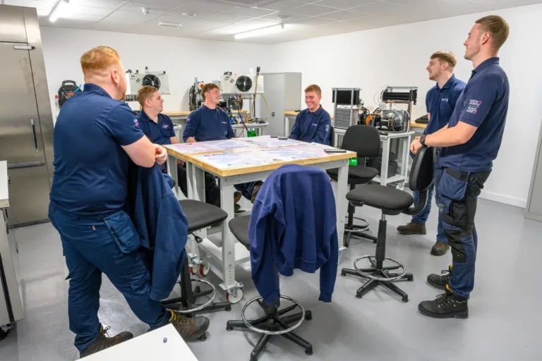 A team of engineers in matching branded polos and sweatshirts in their training room